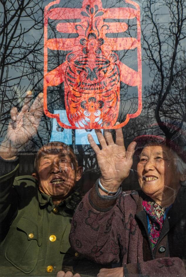 臘月里，霍州市師莊鄉(xiāng)馮南垣村村民師榮光(左)在災(zāi)后重建的新家里貼窗花。(霍州市委宣傳部供圖)