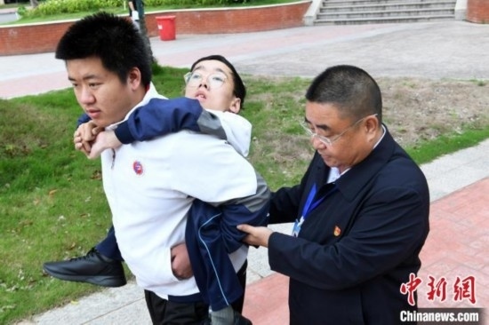 朱金祥背著鐘華強去教室上課的路上，也經(jīng)常碰到值班的校領(lǐng)導和老師前來搭把手。 卓忠偉 攝