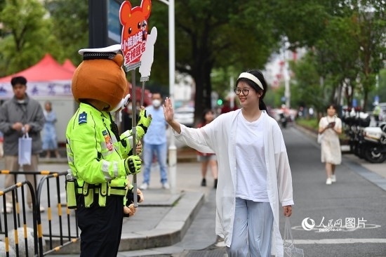 6月7日上午9時(shí)，隨著鈴聲的響起，2023年江西高考正式開考，江西省的53.57萬考生以縣（區(qū)）為單位隨機(jī)安排在全省256個(gè)考點(diǎn)、18968個(gè)考場參加高考。圖為“小熊交警”和考生擊掌鼓勵(lì)。 人民網(wǎng)記者 時(shí)雨攝