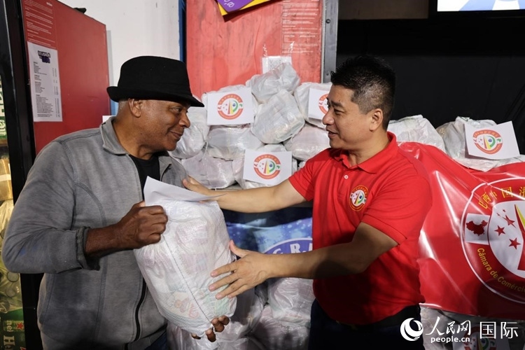 巴西中國浙江商會會長鄭俠茂向社區(qū)居民轉(zhuǎn)交捐贈物資。人民網(wǎng)記者 時元皓攝