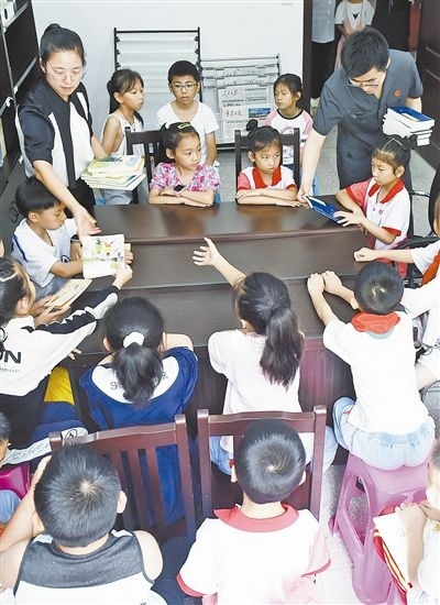  圖④：法院干警為留守兒童發(fā)放暑假讀物。