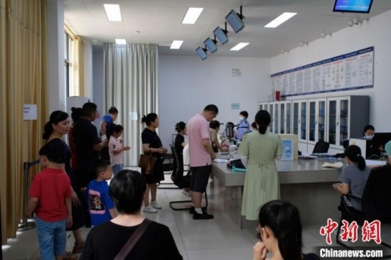 圖為在戶籍辦證廳內(nèi)排隊(duì)等待的家長(zhǎng)和孩子。劉俊聰 攝