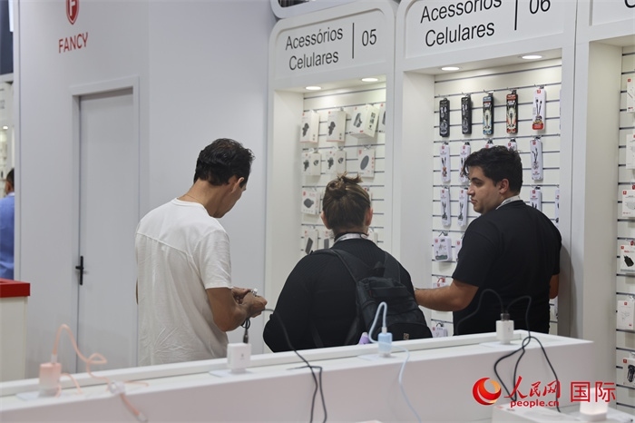 幾名參觀者在一個展臺前了解手機(jī)配件。（人民網(wǎng)記者 時元皓攝）