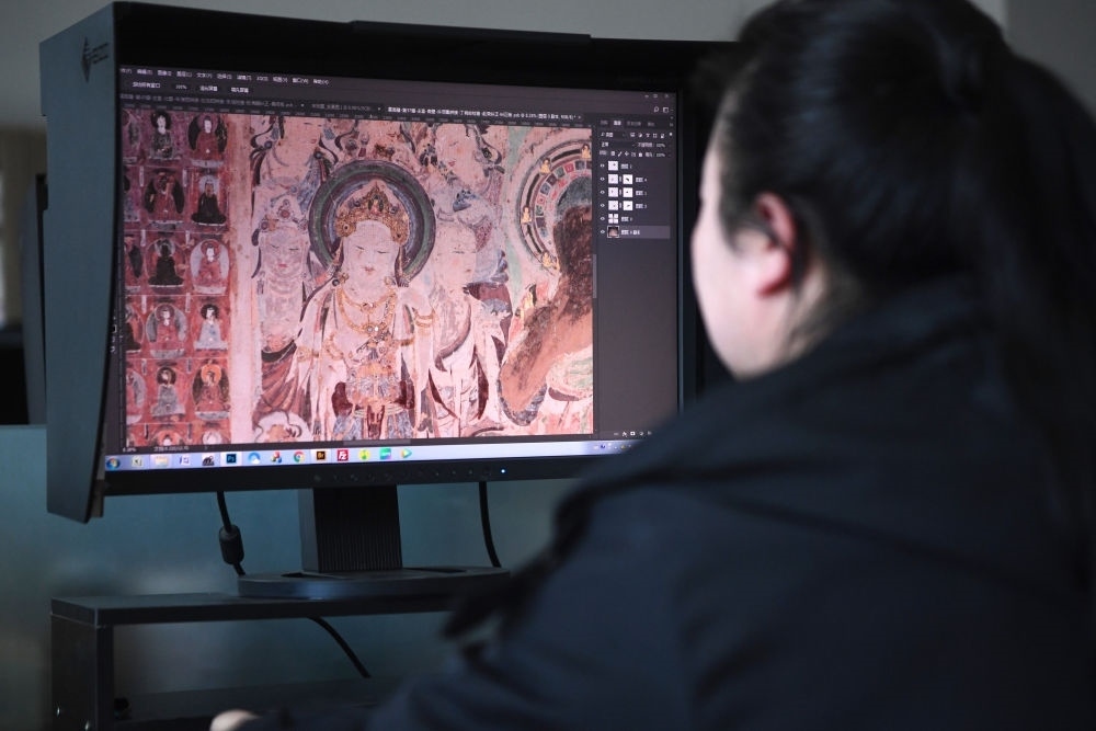 敦煌研究院文物數(shù)字化保護團隊圖像處理人員年海麗在拼接壁畫圖像（2023年4月25日攝）。數(shù)字化探索為莫高窟的保護與傳承開辟了全新路徑，數(shù)字技術讓敦煌文物走出洞窟，跨出國門，走向“永久保存、永續(xù)利用”。新華社記者 陳斌 攝