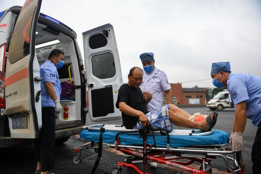 8月1日，在北京市門頭溝區(qū)妙峰山鎮(zhèn)妙峰山民族學(xué)校臨時安置點(diǎn)，北京急救中心工作人員在轉(zhuǎn)運(yùn)一名受傷村民。新華社記者 鞠煥宗 攝