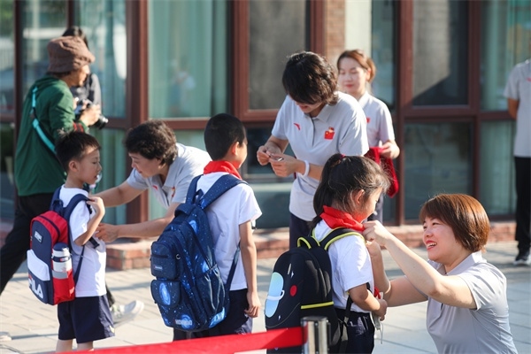 8月30日，雄安史家胡同小學(xué)學(xué)生體驗學(xué)校生活。老師為學(xué)生佩戴?；?。