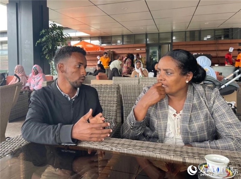 約漢斯（圖左）與德貝拉在友誼廣場咖啡廳交談。人民網(wǎng)記者 趙艷紅攝