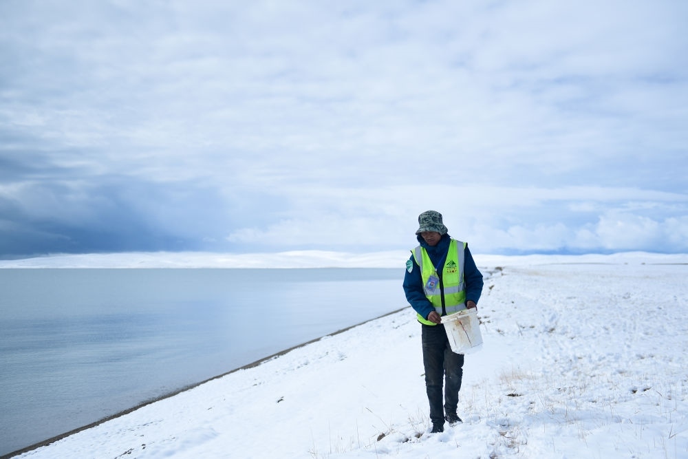 2021年10月20日，在青海省果洛藏族自治州瑪多縣扎陵湖鄉(xiāng)勒那村，三江源國家公園黃河源園區(qū)生態(tài)管護員在扎陵湖邊撿拾垃圾。新華社記者 張龍 攝
