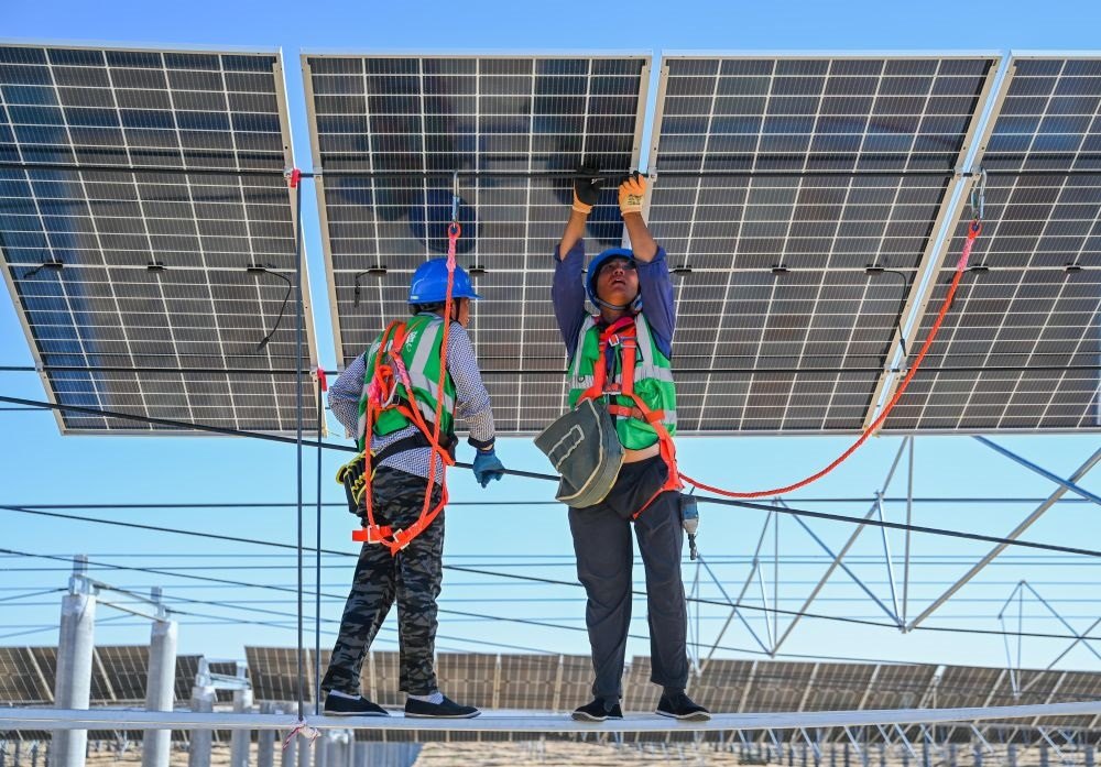 2023年7月22日，工人在位于內(nèi)蒙古杭錦旗庫布其沙漠億利生態(tài)示范區(qū)的蒙西基地庫布其200萬千瓦光伏治沙項目工地安裝光伏板。新華社記者 劉磊 攝