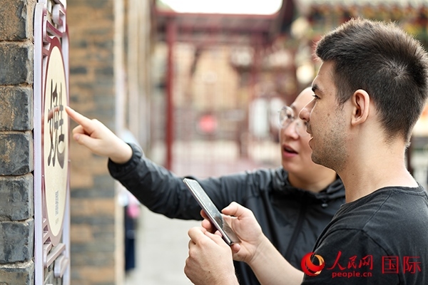 選手安德烈（俄羅斯）在老師指導(dǎo)下學(xué)習(xí)墻壁上張貼的生僻字。人民網(wǎng) 盧鵬宇攝