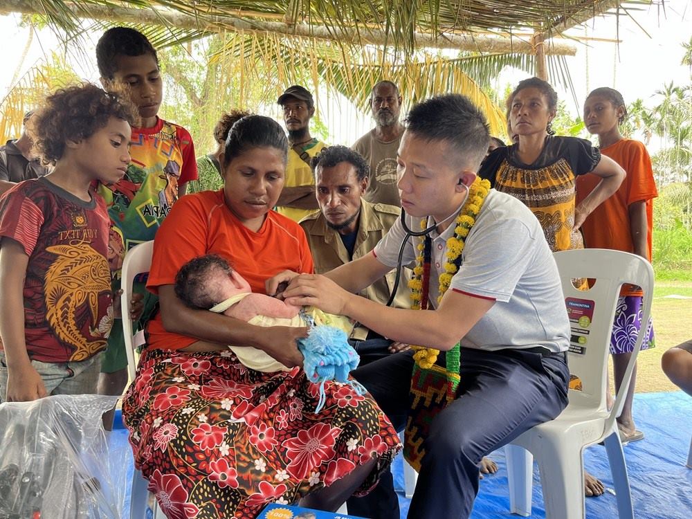 2023年8月5日，在巴布亞新幾內(nèi)亞中央省的一個(gè)村莊里，第12批援巴新中國(guó)醫(yī)療隊(duì)副隊(duì)長(zhǎng)、新生兒科副主任醫(yī)師劉振球?yàn)楫?dāng)?shù)貗雰郝犜\檢查。新華社發(fā)（第12批援巴新中國(guó)醫(yī)療隊(duì)供圖）