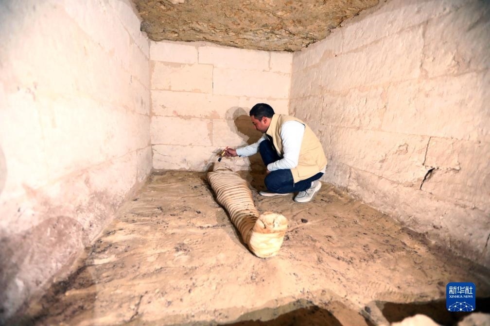 10月15日，在埃及明亞省考古現(xiàn)場(chǎng)，考古人員清理一座石鑿墓中的木乃伊。新華社發(fā)（艾哈邁德·戈馬攝）