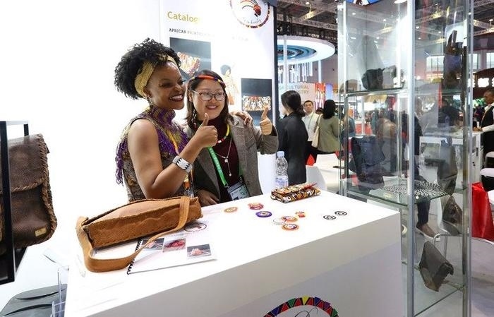 11月6日，一位參觀者（右）在第六屆進博會國家展南非展臺試戴傳統(tǒng)首飾。