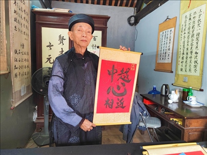越南首都河內(nèi)文廟內(nèi)，阮明珠展示“中越心相近”書法作品。