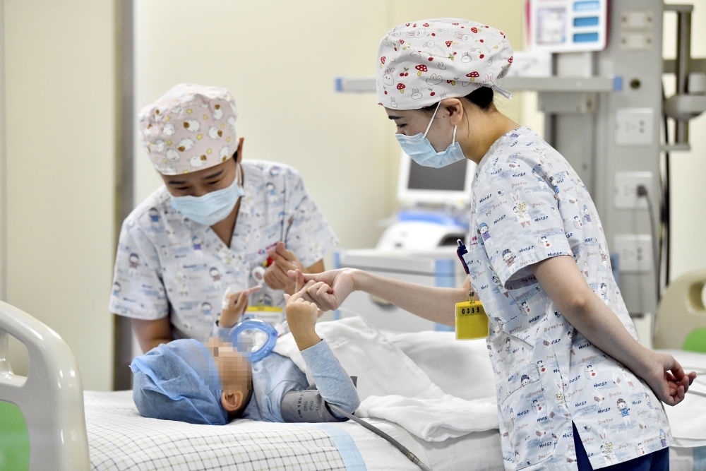 在山東省棗莊市婦幼保健院兒童ICU病房，醫(yī)護(hù)人員為完成靶向治療藥物諾西那生鈉的4歲脊髓性肌萎縮癥患兒加油鼓勁（2022年1月1日攝）。諾西那生鈉注射液是我國首個獲批治療脊髓性肌萎縮癥的進(jìn)口藥物，2019年進(jìn)入中國市場時，每針價格近70萬元。在2021年國家醫(yī)保目錄藥品談判中，以3.3萬元每針的價格進(jìn)入新版醫(yī)保藥品目錄。新華社記者 郭緒雷 攝