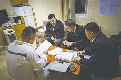 圖②：法官向船長講解相關(guān)法律規(guī)定，查看船舶資料，并與船方辦理扣押船舶的手續(xù)。