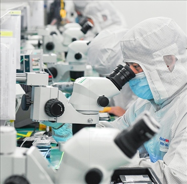 在位于武漢中國光谷的光電器件研發(fā)制造商——武漢光迅科技股份有限公司生產(chǎn)車間內(nèi)，技術人員在光模塊生產(chǎn)線作業(yè)（2023年4月11日攝）。程敏攝/本刊