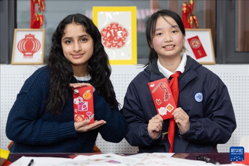 1月28日，美國馬斯卡廷中學學生（左）和復(fù)旦大學第二附屬學校學生展示互相送出的寫有寄語祝福的紅包。 新華社記者 王翔 攝