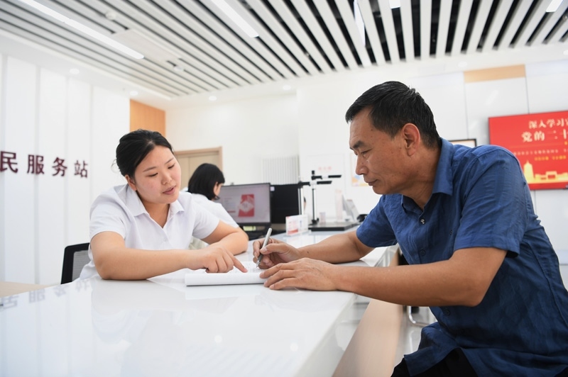 2023年5月23日，河北雄安新區(qū)容東片區(qū)南文營(yíng)社區(qū)居民（右）在社區(qū)便民服務(wù)站辦理業(yè)務(wù)。
