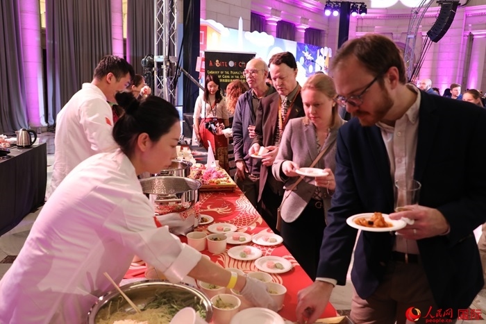 當(dāng)?shù)貢r間3月7日晚，華盛頓聯(lián)合車站廣場舉行駐美使團(tuán)“使館主廚挑戰(zhàn)賽”。圖為當(dāng)?shù)孛癖娫谥袊古_前體驗中國美食。人民網(wǎng)記者 李志偉攝