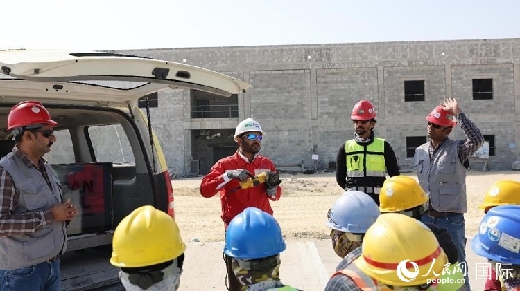 穆薩瓦爾(圖中紅衣人）現(xiàn)場(chǎng)演示工具操作規(guī)范。人民網(wǎng)記者 管克江攝