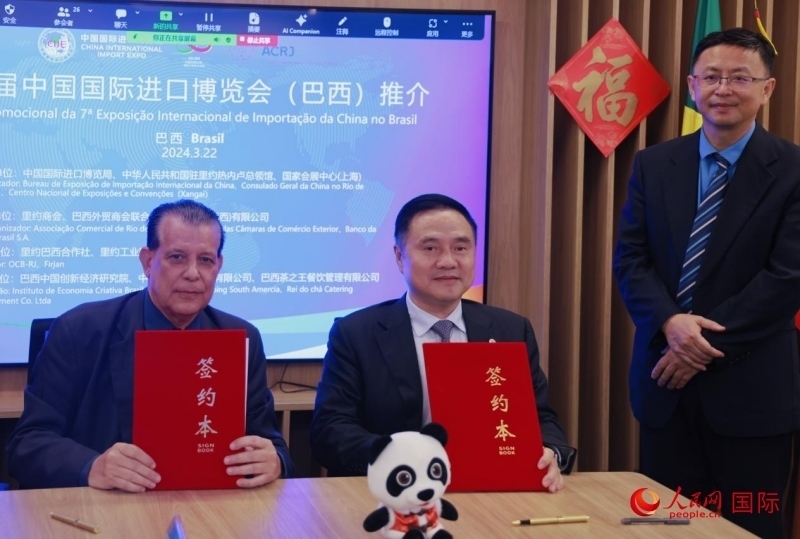 巴西外貿(mào)商會聯(lián)合會會長阿代爾·羅伯托（左）與中國國際進(jìn)口博覽局副局長吳政平（中）現(xiàn)場簽訂協(xié)議。人民網(wǎng)記者 宋亦然攝