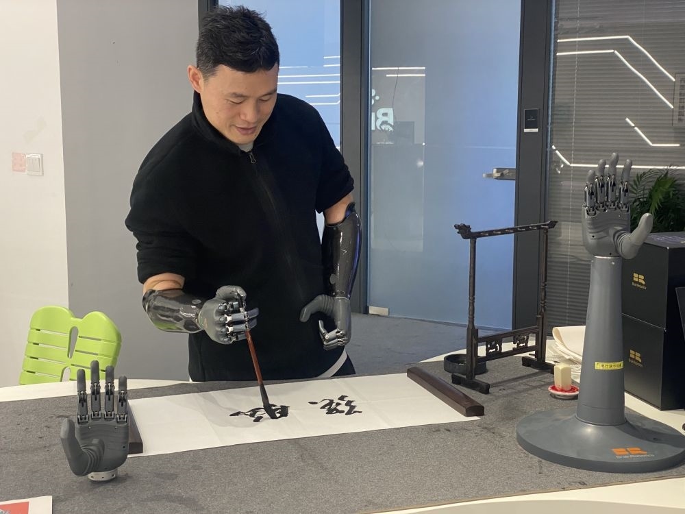 2024年3月29日，在浙江強(qiáng)腦科技有限公司展廳內(nèi)，失去雙手的產(chǎn)品體驗(yàn)官倪敏成依靠智能仿生手寫毛筆字。新華社記者 魏一駿 攝