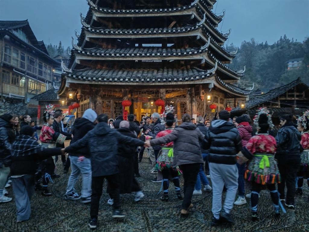 法國青年與當?shù)卮迕駹渴痔?。新華社記者 羅羽 攝