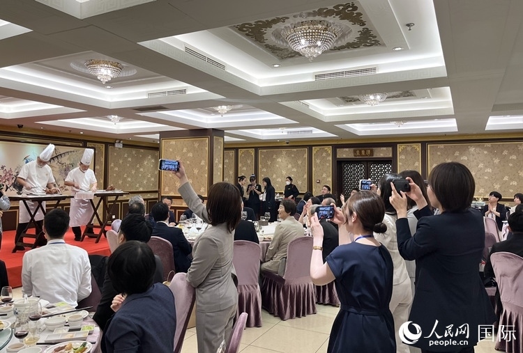 國家級(jí)非物質(zhì)文化遺產(chǎn)、全聚德片鴨工藝吸引代表團(tuán)成員拍照留念。