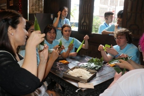 6月9日，美國(guó)青年代表在重慶永川松溉古鎮(zhèn)體驗(yàn)包粽子。新華社記者 周思宇 攝