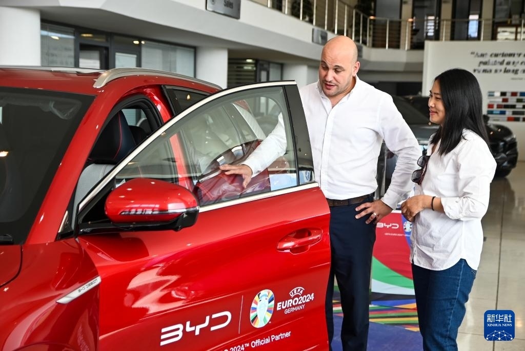 2024年5月29日，在馬耳他比爾基卡拉，馬耳他哈桑-扎米特汽車公司首席執(zhí)行官德古阿拉（左）介紹一輛比亞迪純電動汽車。新華社發(fā)（喬納森·博格 攝）