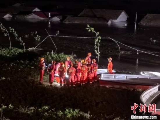  7月6日凌晨3時，在湖南岳陽華容縣團洲垸洞庭湖一線堤防，救援人員剛剛完成一次救援任務(wù)，遠處是被淹的民房。中新社記者 白祖偕 攝