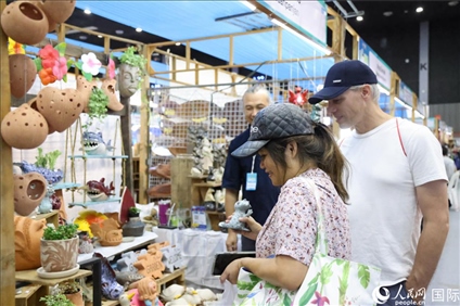 游客在蘭納博覽會特色展位上選購工藝品。人民網(wǎng)記者楊一攝