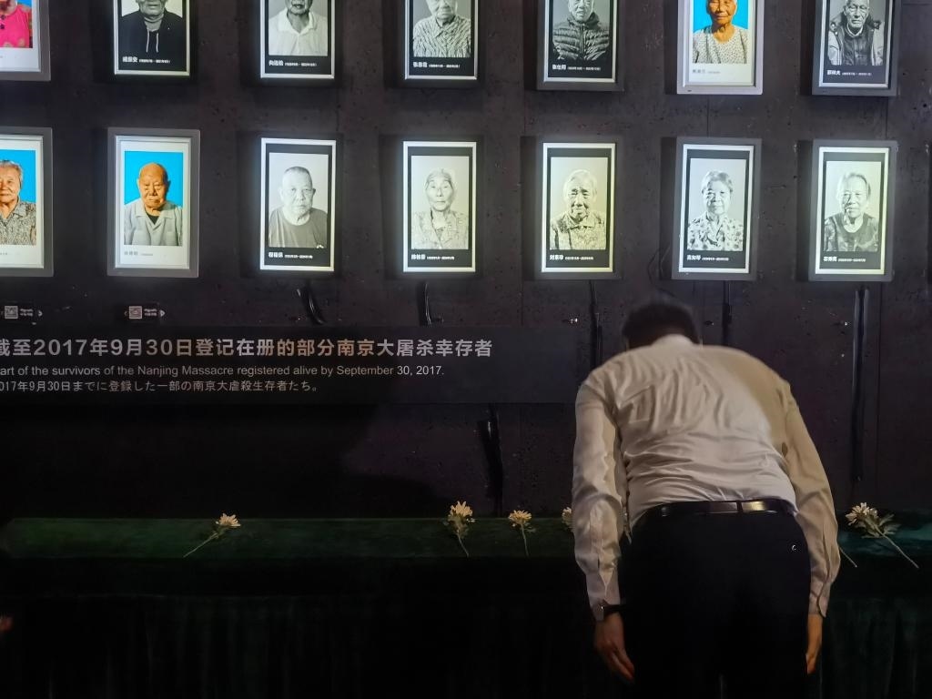 7月18日，人們向離世的南京大屠殺幸存者獻(xiàn)花、鞠躬。新華社記者邱冰清 攝