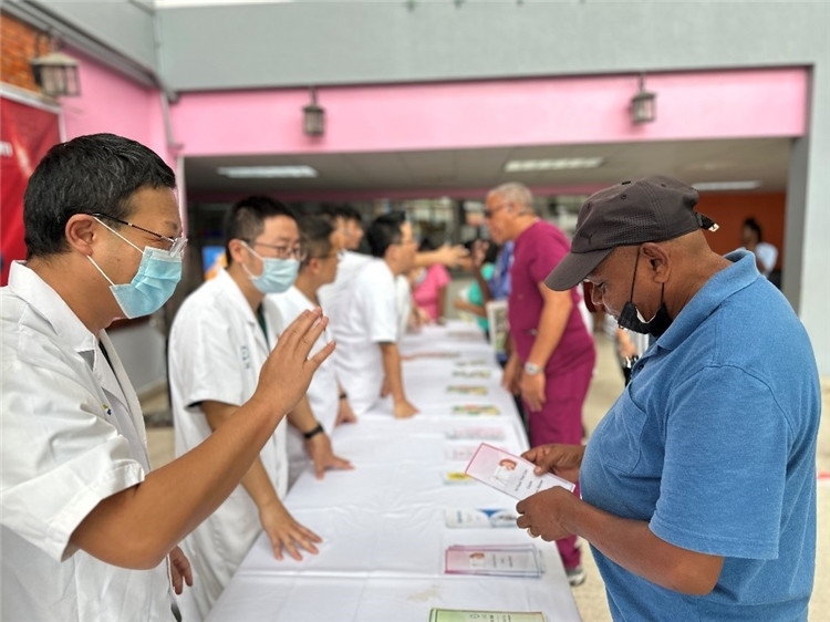 援圭醫(yī)療隊隊員們在啟動儀式上為當?shù)孛癖姺职l(fā)宣傳手冊。中國援助圭亞那醫(yī)療隊供圖