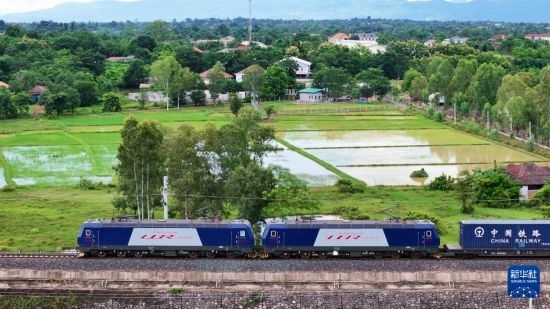 8月5日，由老撾籍火車司機(jī)獨(dú)立駕駛的滿載貨物的列車駛出萬象站，向中國昆明進(jìn)發(fā)（無人機(jī)照片）。新華社發(fā)（楊永全 攝）