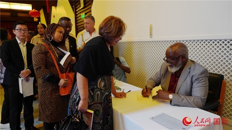 譚哲理在活動(dòng)現(xiàn)場(chǎng)簽名贈(zèng)書。人民網(wǎng) 劉暢攝