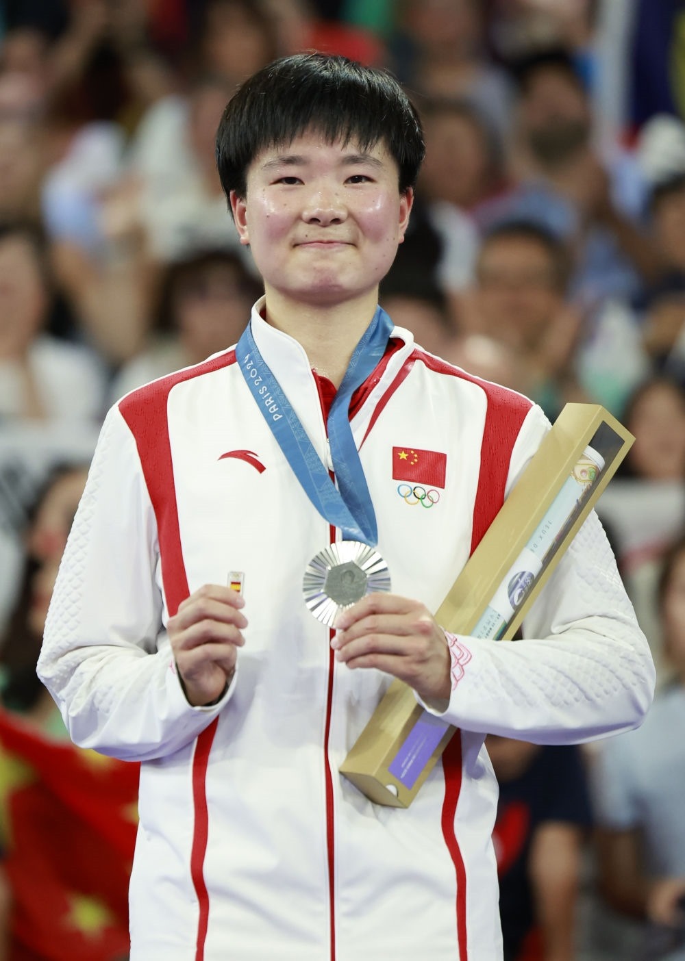 巴黎奧運會羽毛球女子單打亞軍、中國選手何冰嬌在頒獎儀式上一手握著銀牌，一手握著西班牙奧委會徽章（2024年8月5日攝）。新華社記者 任正來 攝