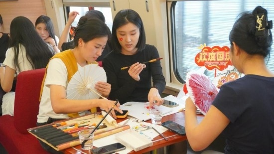 10月1日，旅客們?cè)贕1634次列車上給油紙傘作畫。新華社記者周義 攝