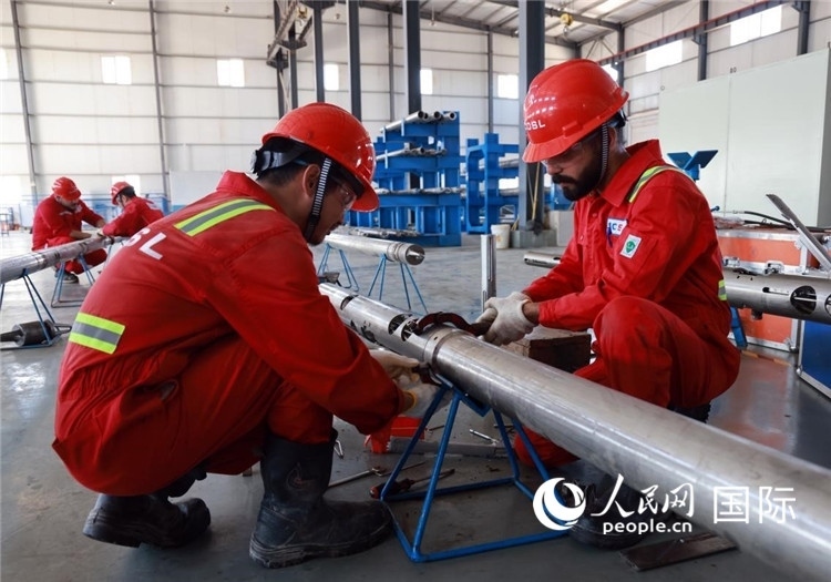 中伊員工共同在檢修鉆井設(shè)備。人民網(wǎng)記者管克江攝