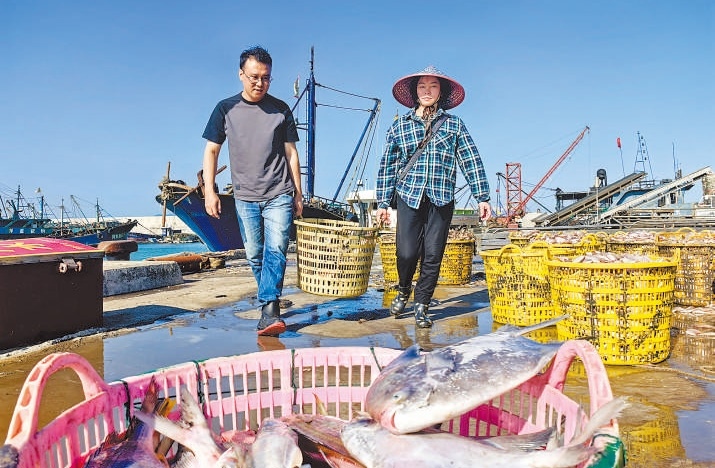 許小斌（左）和漁民一起搬運(yùn)海鮮。本報(bào)記者 付 文攝