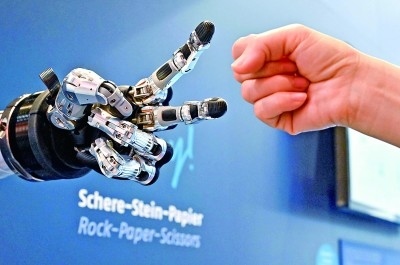 在德國漢諾威工博會上，參觀者與一款智能機器人進行“石頭剪子布”游戲。新華社發(fā)