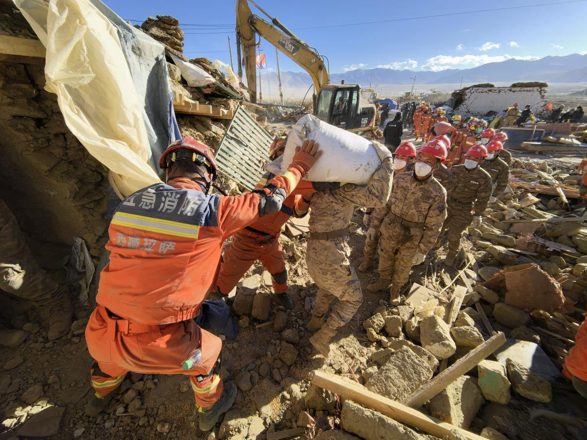 1月11日，定日縣長所鄉(xiāng)古榮村，應(yīng)急消防等救援人員排隊(duì)接力搶運(yùn)掩埋在倒塌房屋下的群眾財(cái)物。人民日?qǐng)?bào)記者楊翹楚攝