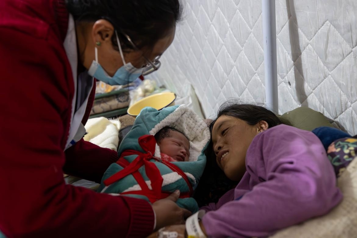 1月10日，定日縣中心醫(yī)院的婦產(chǎn)科醫(yī)生悉心照看一位母親和她懷里的新生兒。人民日?qǐng)?bào)記者張武軍攝