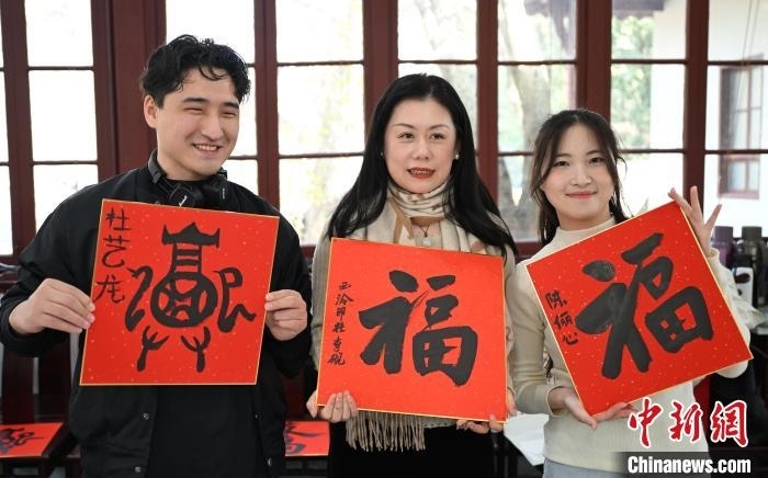 1月20日，外籍留學(xué)生和西泠印社社員李硯(中)展示各自創(chuàng)作的福貼。當(dāng)日，來自巴西、馬來西亞、加納、哈薩克斯坦的外籍留學(xué)生在浙江杭州西泠印社體驗(yàn)福貼、春聯(lián)和篆刻，感受古老的中國傳統(tǒng)文化。中新社記者 王剛 攝