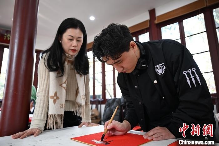 1月20日，外籍留學(xué)生在西泠印社社員李硯指導(dǎo)下寫福。當(dāng)日，來自巴西、馬來西亞、加納、哈薩克斯坦的外籍留學(xué)生在浙江杭州西泠印社體驗(yàn)福貼、春聯(lián)和篆刻，感受古老的中國傳統(tǒng)文化。中新社記者 王剛 攝