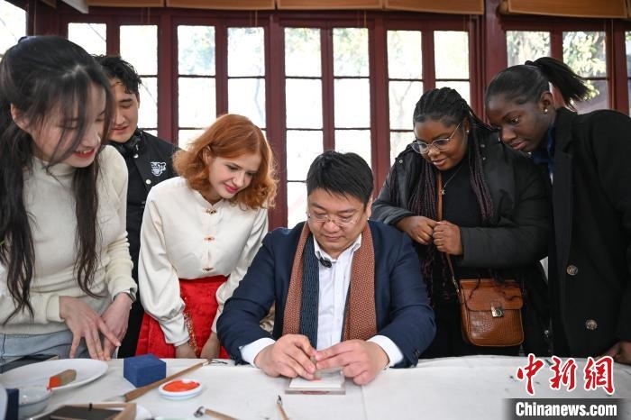 1月20日，篆刻家王臻向外籍留學(xué)生展示篆刻印章。當(dāng)日，來自巴西、馬來西亞、加納、哈薩克斯坦的外籍留學(xué)生在浙江杭州西泠印社體驗(yàn)福貼、春聯(lián)和篆刻，感受古老的中國傳統(tǒng)文化。中新社記者 王剛 攝