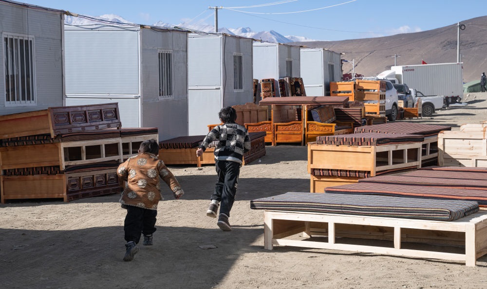 2025年1月13日，在定日縣嘎旦村，兩個孩子在剛運(yùn)來的兩排藏床間奔跑。新華社記者丁增尼達(dá) 攝