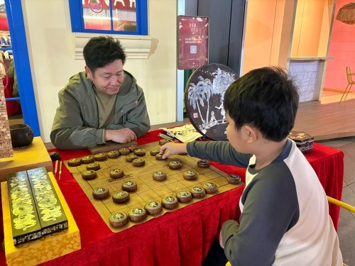 柯秋楓與市民下椰雕象棋。人民網(wǎng) 陳葉欣攝