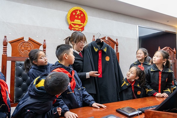 圖②：干警向同學(xué)們介紹法袍。